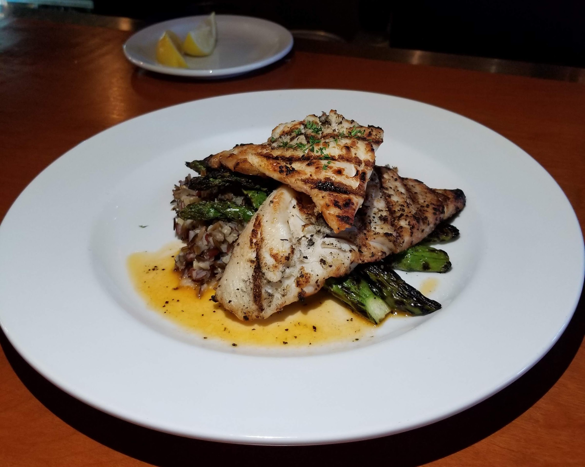 Grilled whitefish over wild rice with charred asparagus and butter sauce — Schnitz Ada Grill dinner plate