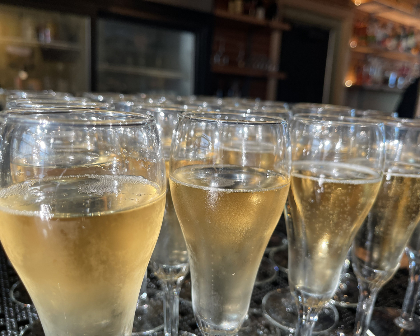 Rows of sparkling wine glasses poured at the bar